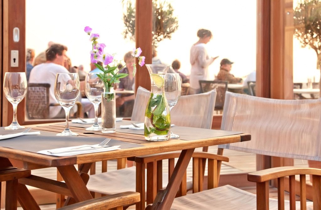 Sonnenterrasse eines Restaurants mit eingedeckten Tischen